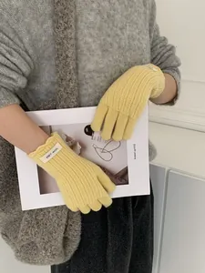 Detail of yellow ribbed wool knit gloves with ERRT WOOL label shown on a model