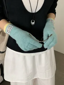 Detail of light blue knit gloves with yellow ribbed cuffs and vintage woven brand label