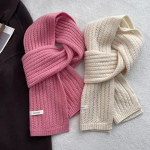 Dettaglio di sciarpe in maglia rosa e crema con etichetta in 100% pura lana