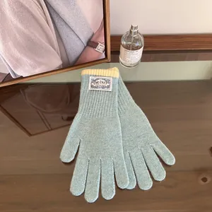 Detail of light blue knitted gloves showing soft rib texture and yellow contrast cuffs