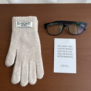 Macro shot of warm oatmeal knitted gloves with brand label on a wooden desk