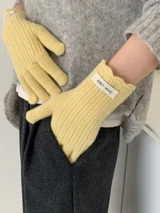 Macro detail of yellow wool knit gloves featuring ribbed texture and wave lace cuffs
