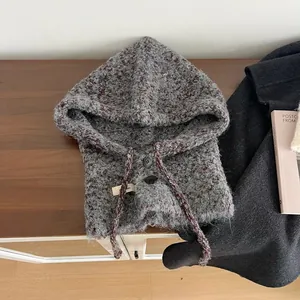 Detail van wollen gebreide bivakmuts met dubbele knoopsluiting op houten tafel
