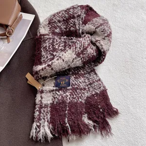 Detail shot of burgundy plaid scarf with tassels on textured carpet background