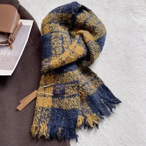 Detail of blue and yellow checkered scarf with fringes and minimalist brand label