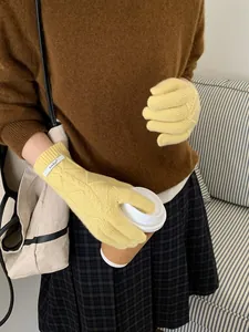 Detail of yellow merino wool gloves with cable knit texture and branded wrist label