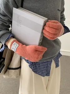 Close-up of pink knit gloves with rib cuffs and blue logo patch detail