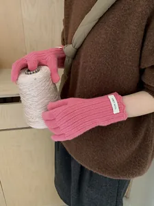 Detailed macro view of pink wool knit glove featuring wavy edges and ERET WOOL label