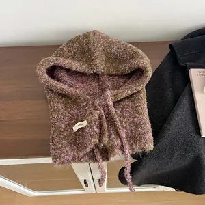 Detail van groen en roze gebreide bivakmuts met woltextuur en klein geweven label op hout