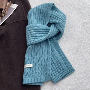 Dettaglio di sciarpa azzurra in 100% pura lana con maglia a coste spessa ed etichetta