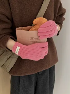 Detail of pink ribbed wool knit gloves with white ERET-WOOL label and soft texture