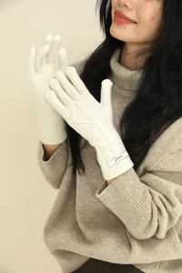 Detail of off-white merino wool knitted gloves with textured cable knit patterns