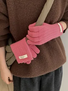 Detailed shot of pink wool knit gloves with elastic ribbed cuffs and white brand label