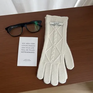 Detailed cable-knit texture of merino wool gloves with a branded metal label