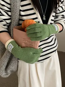 Detailed view of grass green knitted gloves with white contrast roll-edge cuffs
