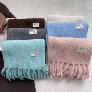 Various soft wool scarves with tassels in pastel colors, warm winter fashion accessory