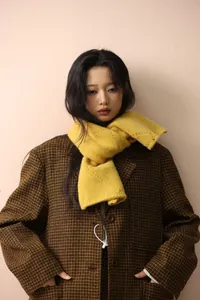 Detail of a bright yellow chunky knit scarf paired with a brown checkered blazer jacket
