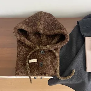Detail van bruine gebreide bivakmuts met knopen en trekkoord op een houten oppervlak