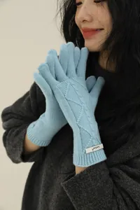 Detail view of light blue merino wool knit gloves with cable pattern and wrist tag
