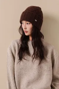 Detail of dark brown Australian wool knit beanie with diamond pattern and metal logo