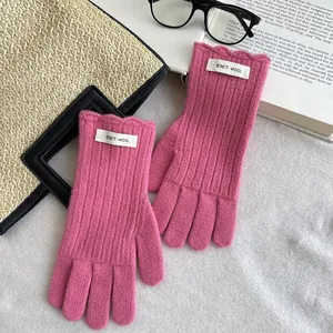 Detail of rose pink wool knit gloves with scalloped edges and ERET WOOL label