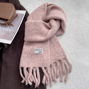 Close-up of pink wool scarf featuring long tassels and a rectangular woven brand tag