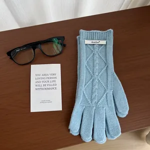 Detail of light blue merino wool knitted gloves with diamond pattern on wooden background