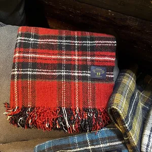Gros plan d'une écharpe en cachemire rouge à carreaux avec pompons et étiquette tissée