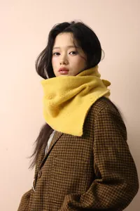 Close-up of ginger yellow chunky cable knit scarf with button detail on plaid blazer