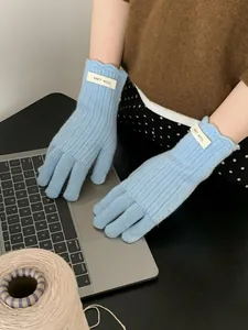 Close-up of light blue wool knit gloves with ERET·WOOL woven label on ribbed cuff