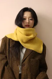 Close-up of bright yellow cable knit scarf paired with classic brown checkered wool blazer