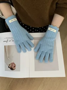 Detail of light blue wool knitted gloves with ribbed texture and scalloped wavy cuff