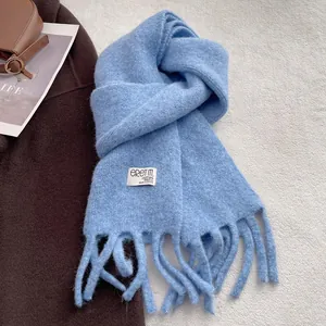 Close-up of light blue wool blend scarf with fringe detail and woven brand label