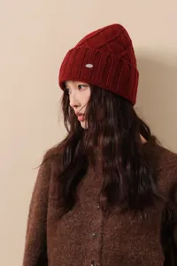 Close-up of deep red Australian wool cable knit hat with a silver metal logo plate