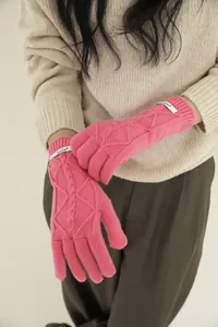 Detail view of pink merino wool knitted gloves with cable pattern and woven label