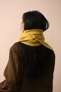 Detailed close-up of ginger yellow knit scarf showing soft wool texture and weave pattern