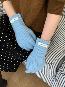 Close-up of light blue wool knitted gloves with soft ribbed texture and brand label
