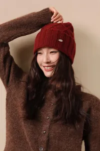 Close-up of wine red wool knit beanie with thick texture and small metal button detail