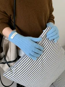 Detail of light blue wool knitted gloves with ribbed cuff and branded ERET wool label