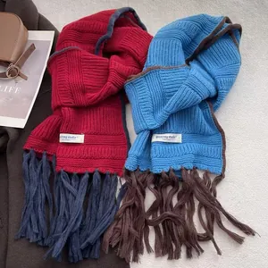 Blue and red chunky knit winter scarves with tassels on elegant wool coats in a cozy setting