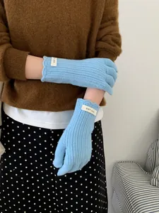 Detail of light blue wool knit gloves with wavy cuffs and textured vertical stripes
