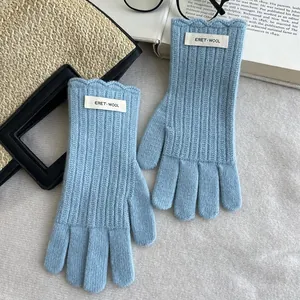 Detail of light blue wool knitted gloves featuring vertical ribbing and wavy cuff edges