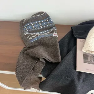Detail view of Fair Isle knit balaclava scarf with blue and white pattern on wood background
