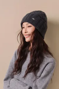 Close-up of dark grey wool knit hat showing vertical rib texture and metal logo plate