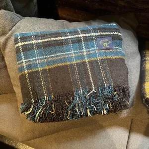 Détail d'une écharpe à carreaux bleu marine et marron avec franges et étiquette tissée