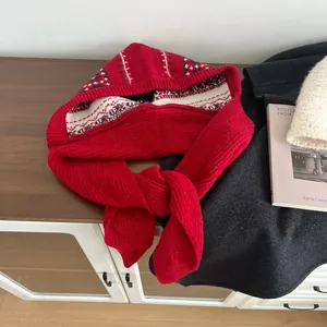 Detail of red knit balaclava scarf with Fair Isle pattern on warm wood background