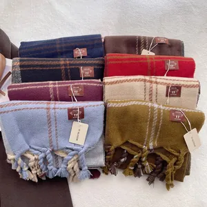 Detailed flat lay of colorful plaid scarves with chunky tassels and brand labels