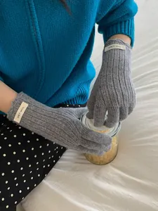 Close-up of grey wool knit glove featuring a minimalist branded label and ribbed wrist cuff
