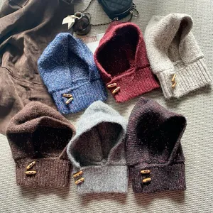 Détail de cagoules en tricot avec boutons en bois en six couleurs sur un tapis