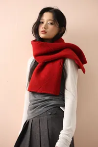 Detail of red cable knit scarf with thick wool texture and Korean style layering